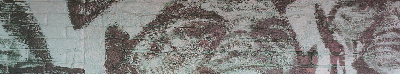 Graffiti art painted on a brick wall, featuring abstract, swirling dark and light patterns with textured brush strokes. Subtle colors of green and purple are visible.