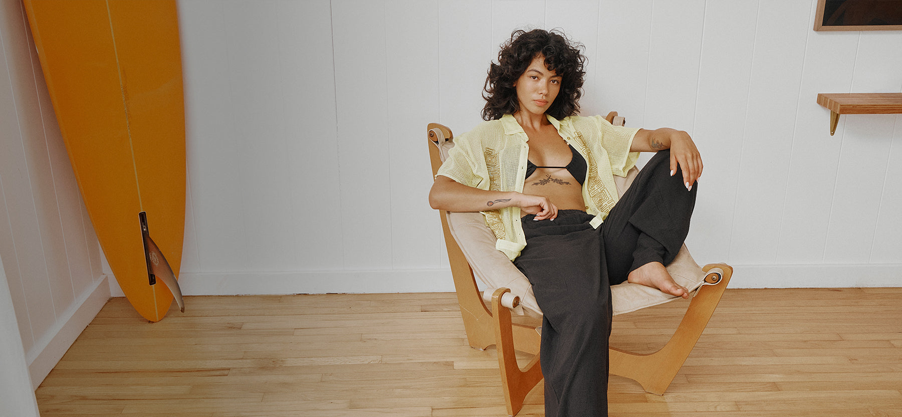 Woman sitting on a chair in a room with a white wall and wooden floor.