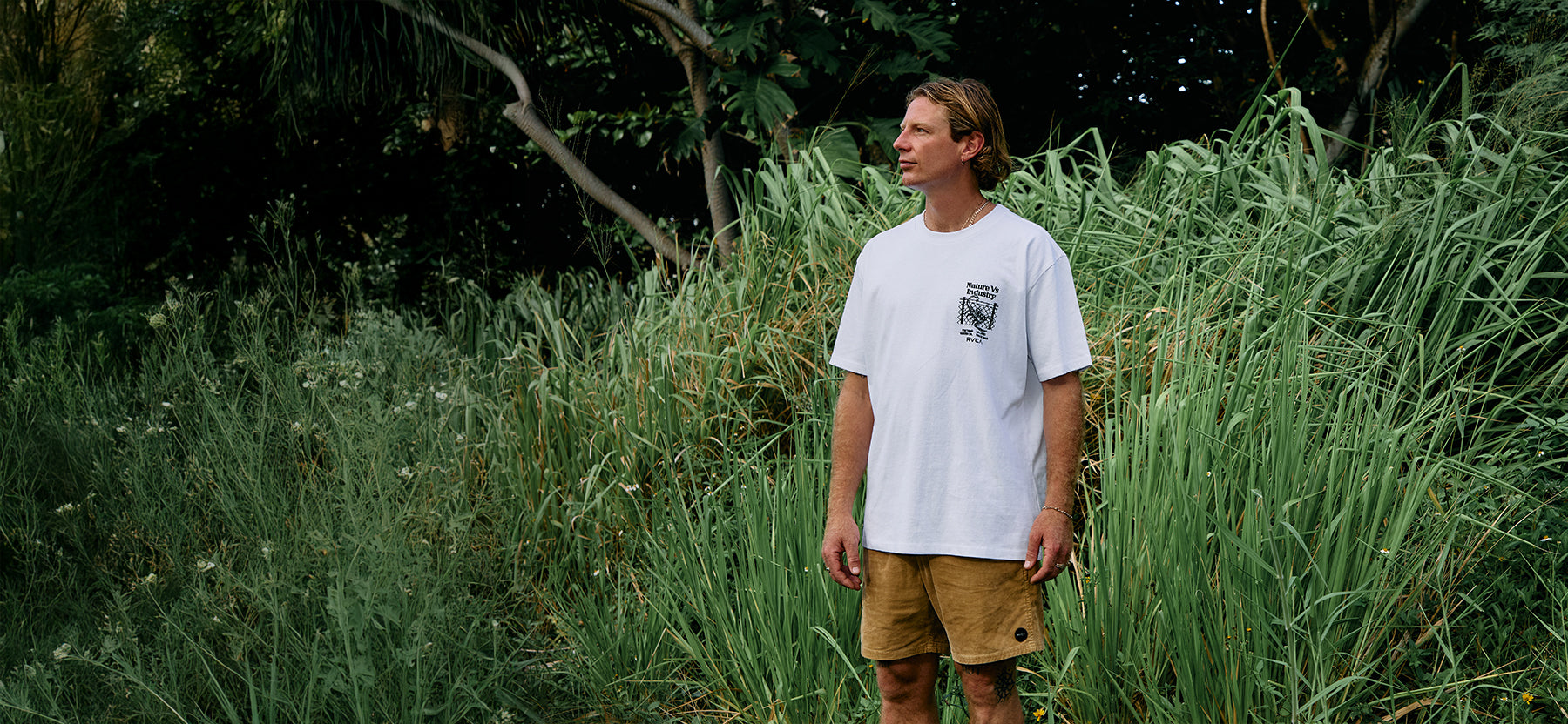 Man standing in tall green grass with a blurred background