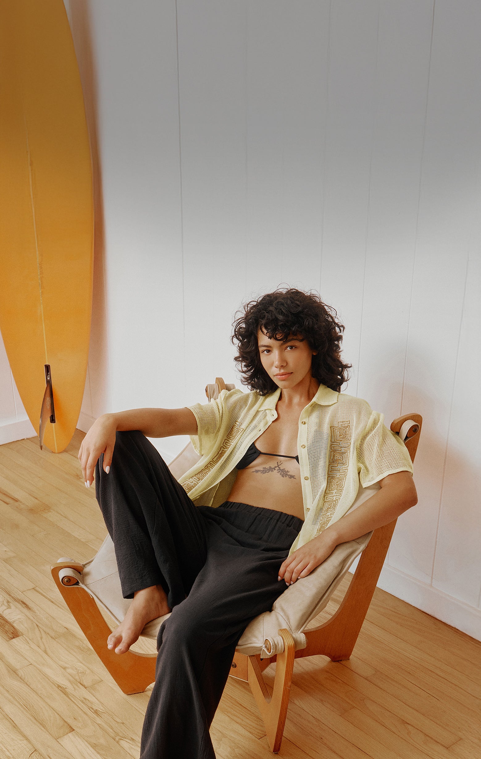 Person sitting on a chair in a room with a white wall and wooden floor.