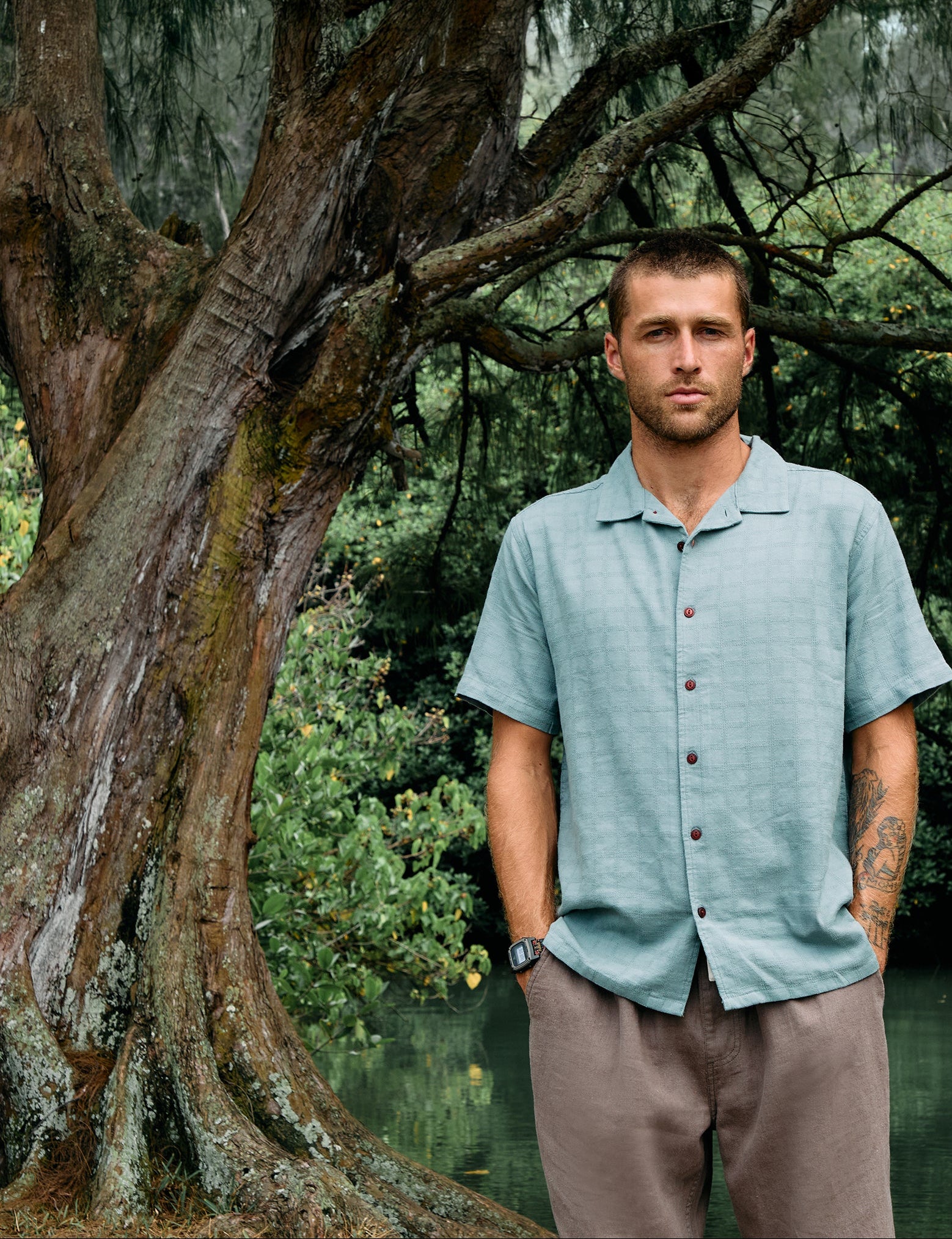 Man standing in a natural setting with trees and greenery