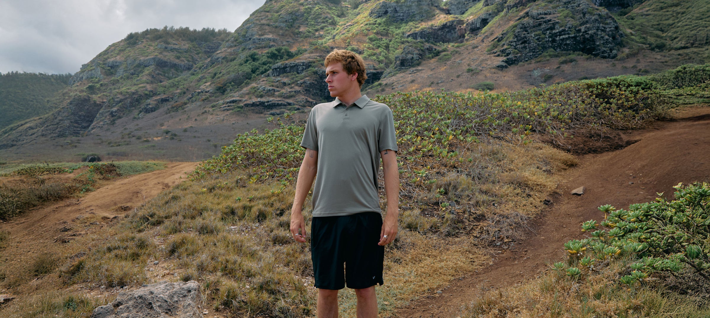 Man standing on a dirt path in a mountainous landscape