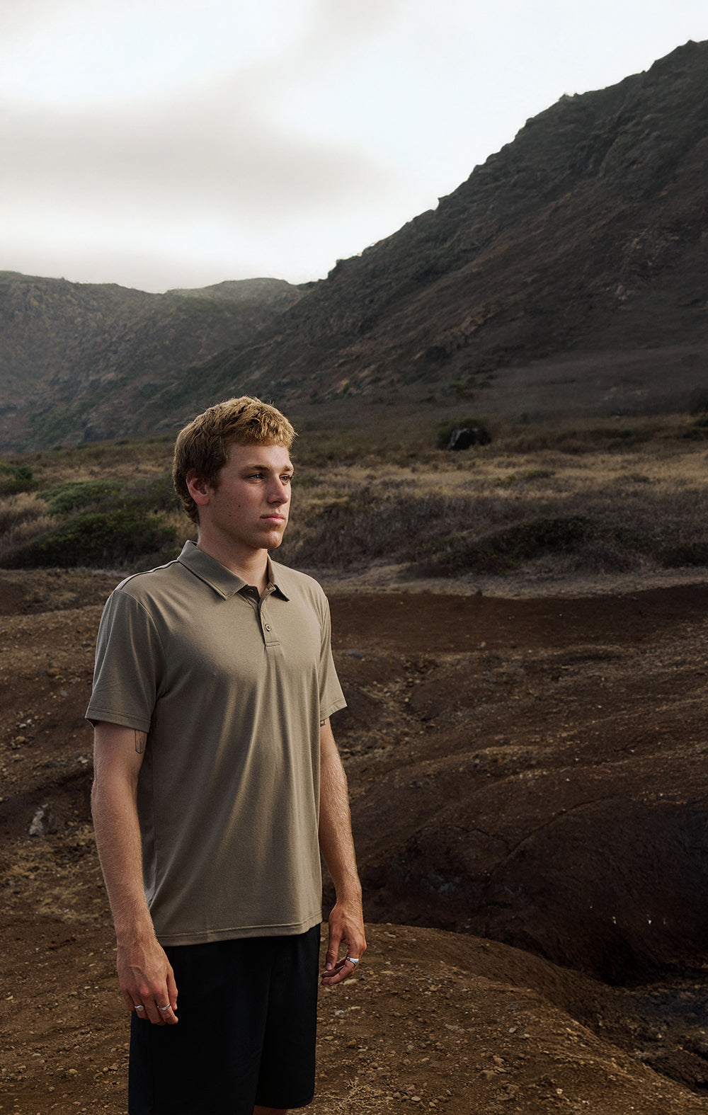 Man standing in a desert landscape with mountains in the background