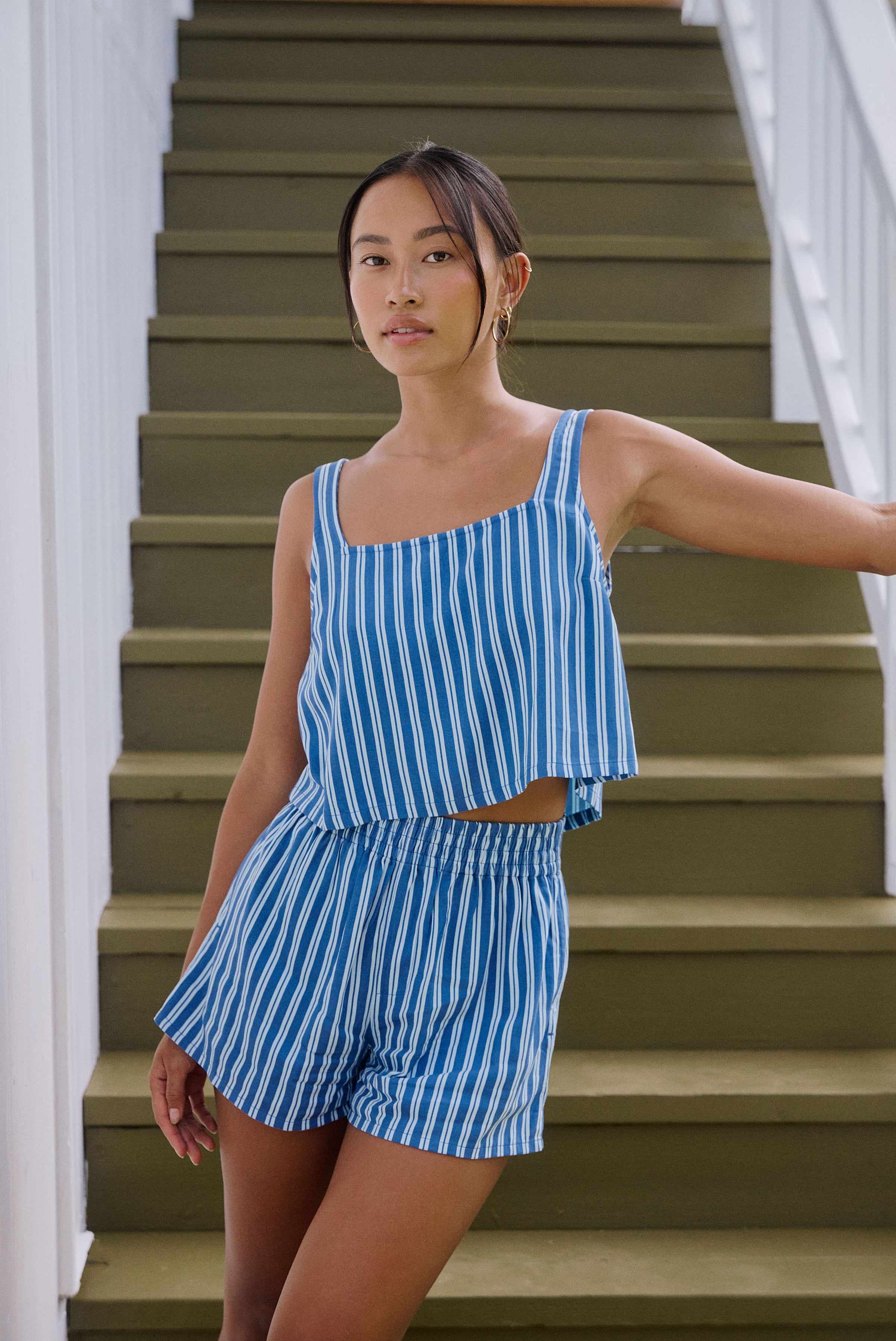 Woman in a blue and white striped outfit standing on a staircase