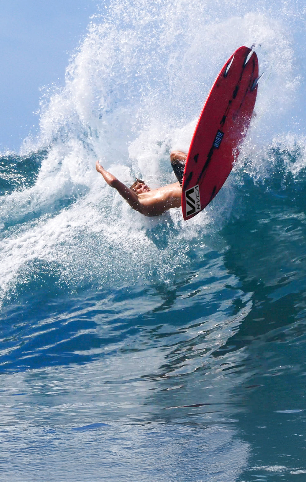 Surfer on a red surfboard performing a trick over a wave.