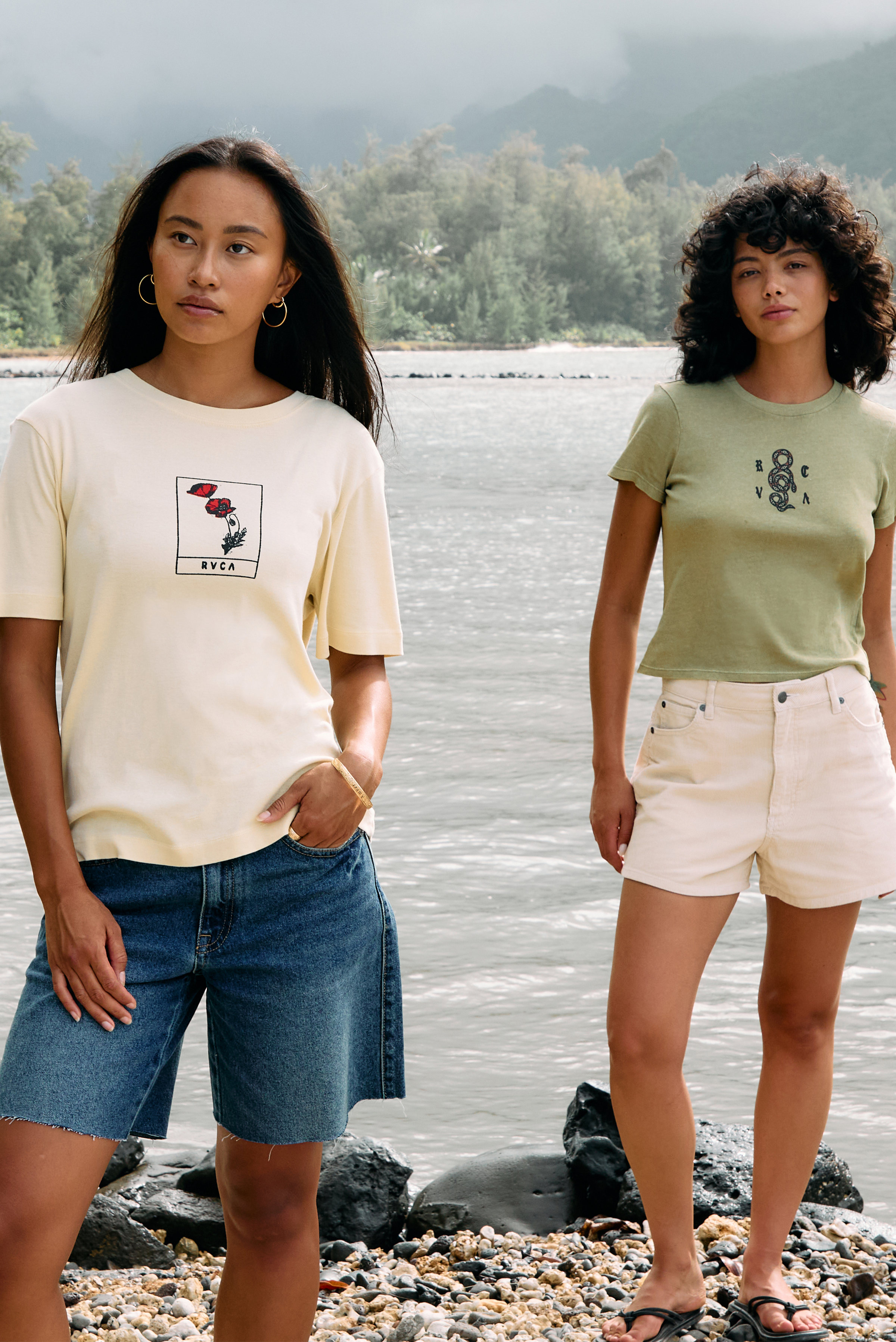 Two women standing by a body of water wearing t-shirts with graphic designs.