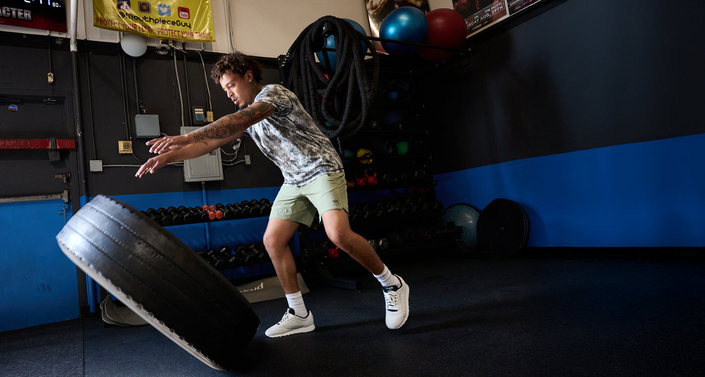 Person performing a workout with a tire in a gym setting