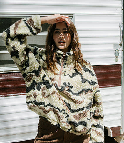 Person wearing a patterned sweater in front of a trailer.