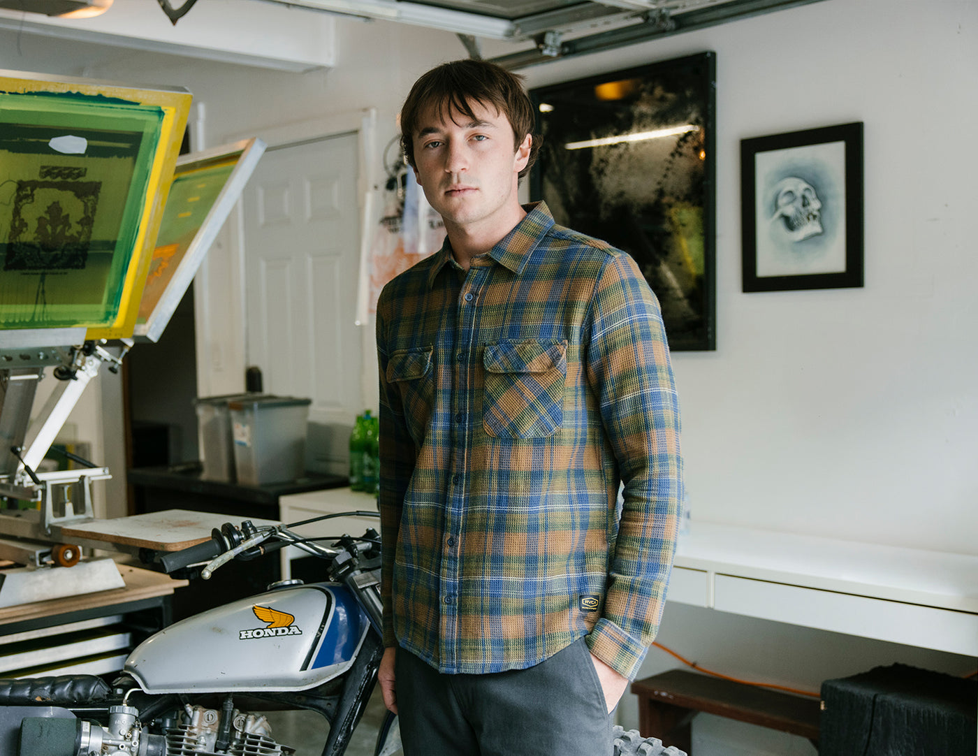 Man in a plaid shirt standing in a room with artwork on the walls