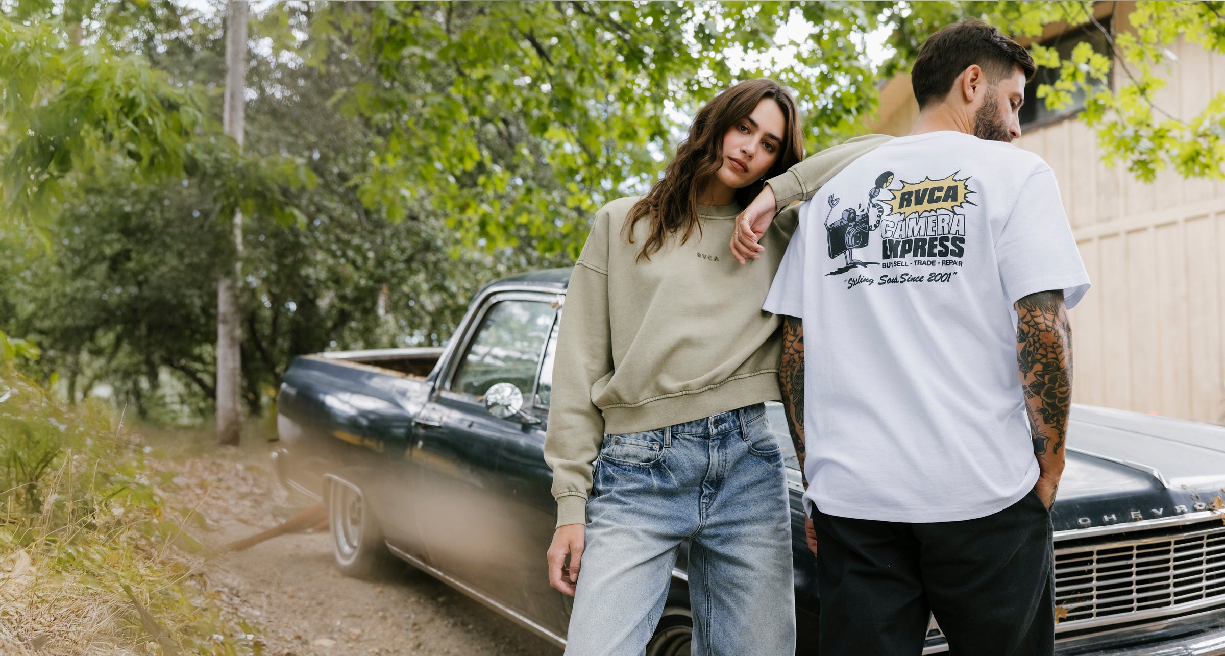 Two people standing next to a classic car with a scenic background