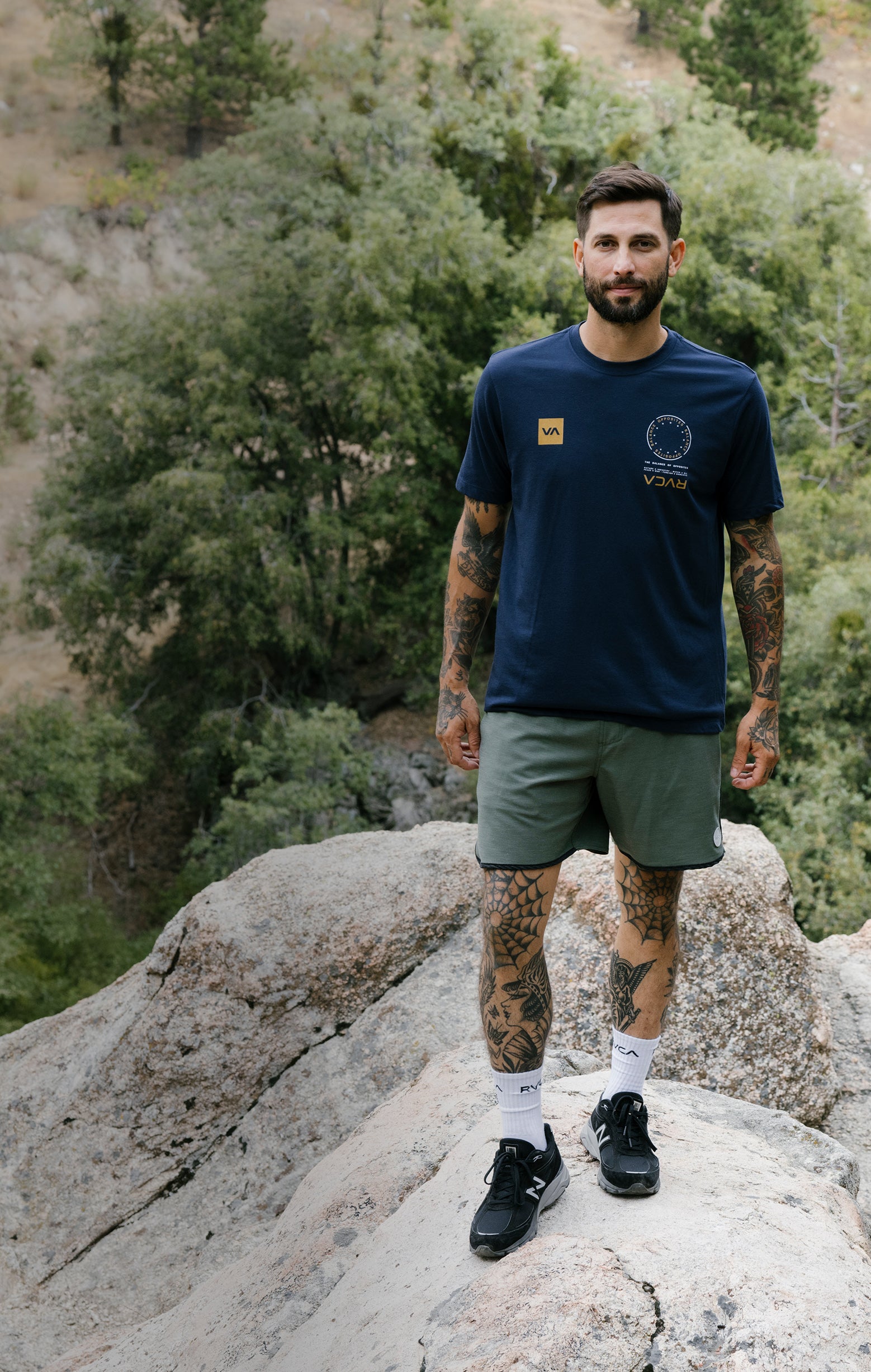Man standing on a rocky outcrop with trees in the background