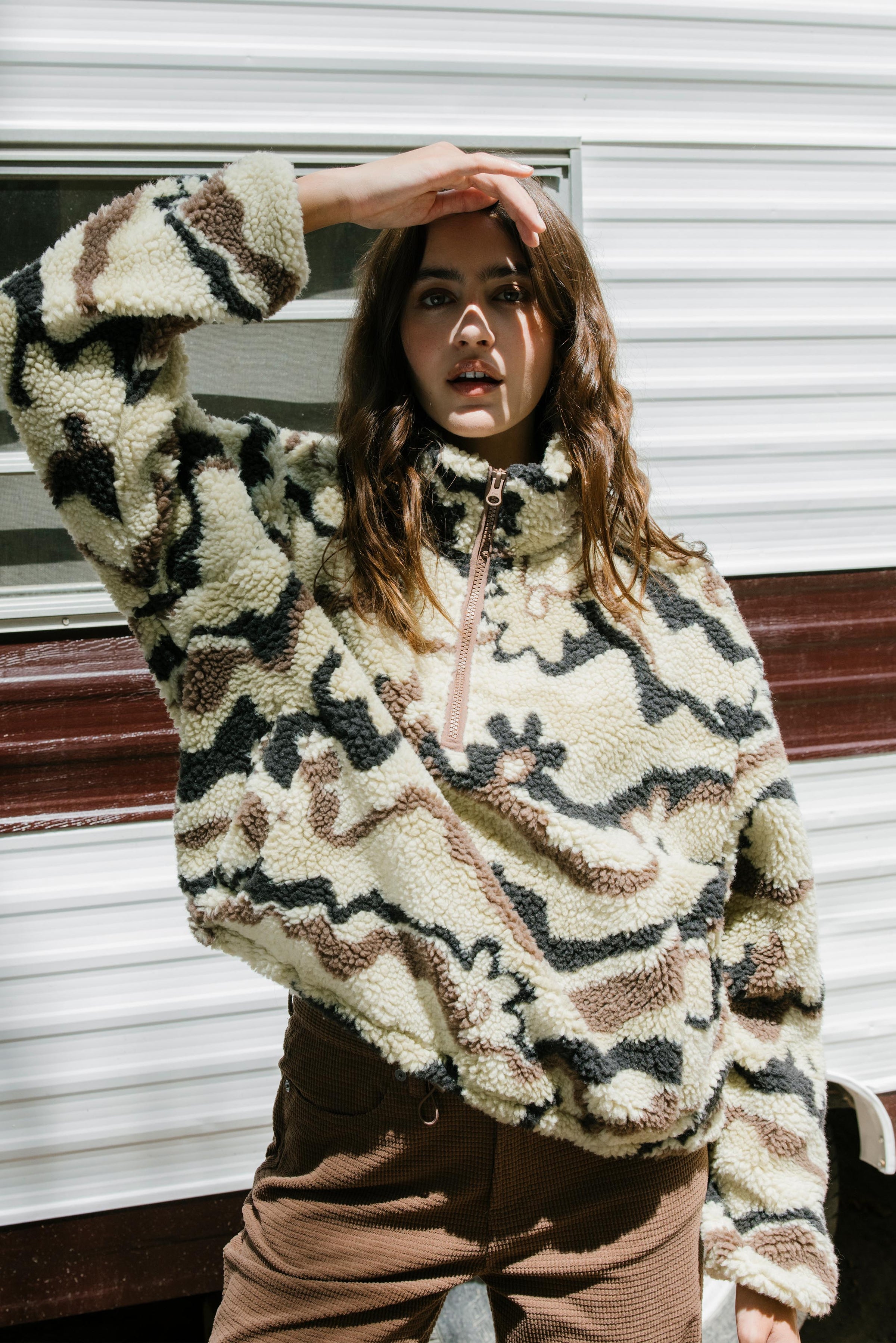 Person wearing a patterned fleece jacket in front of a building.