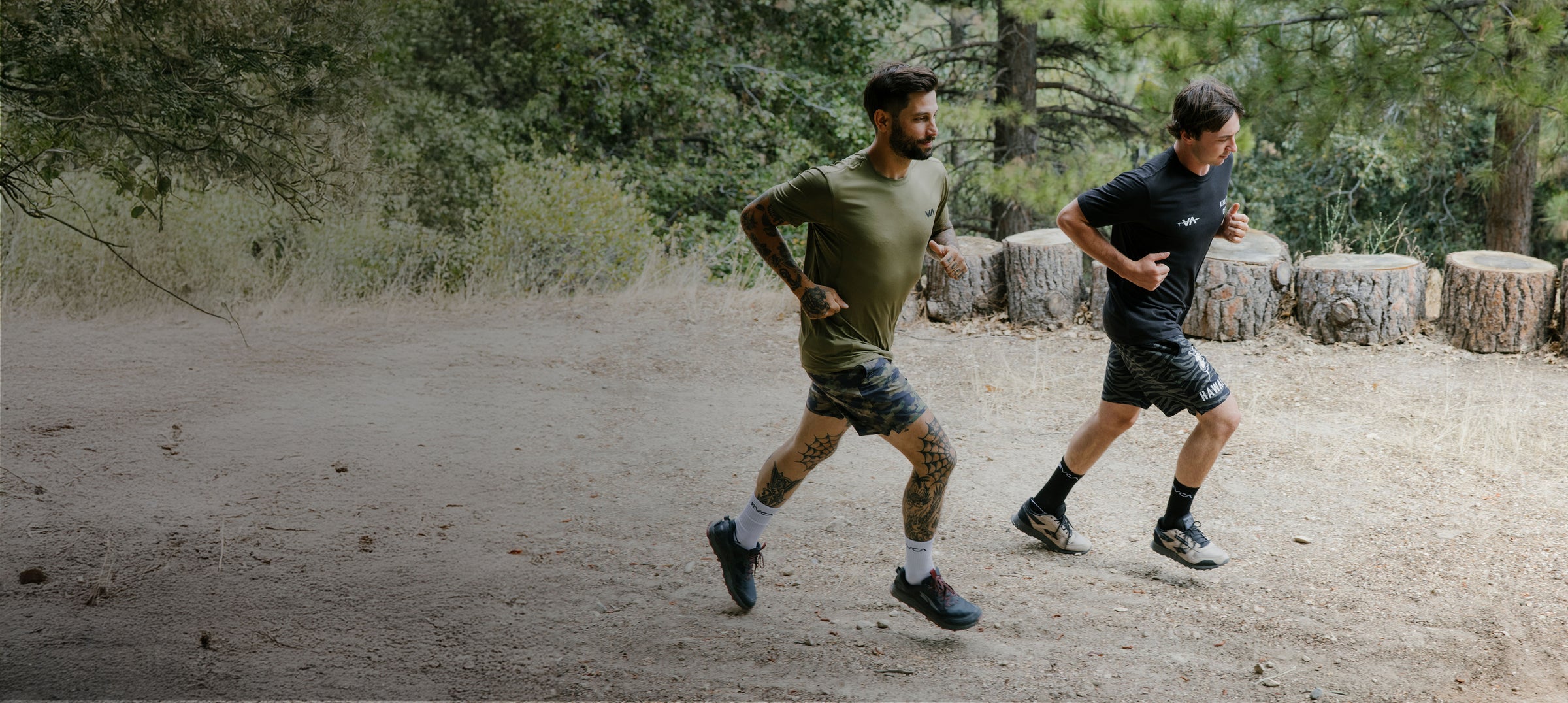 Two men running on a dirt path in a forested area