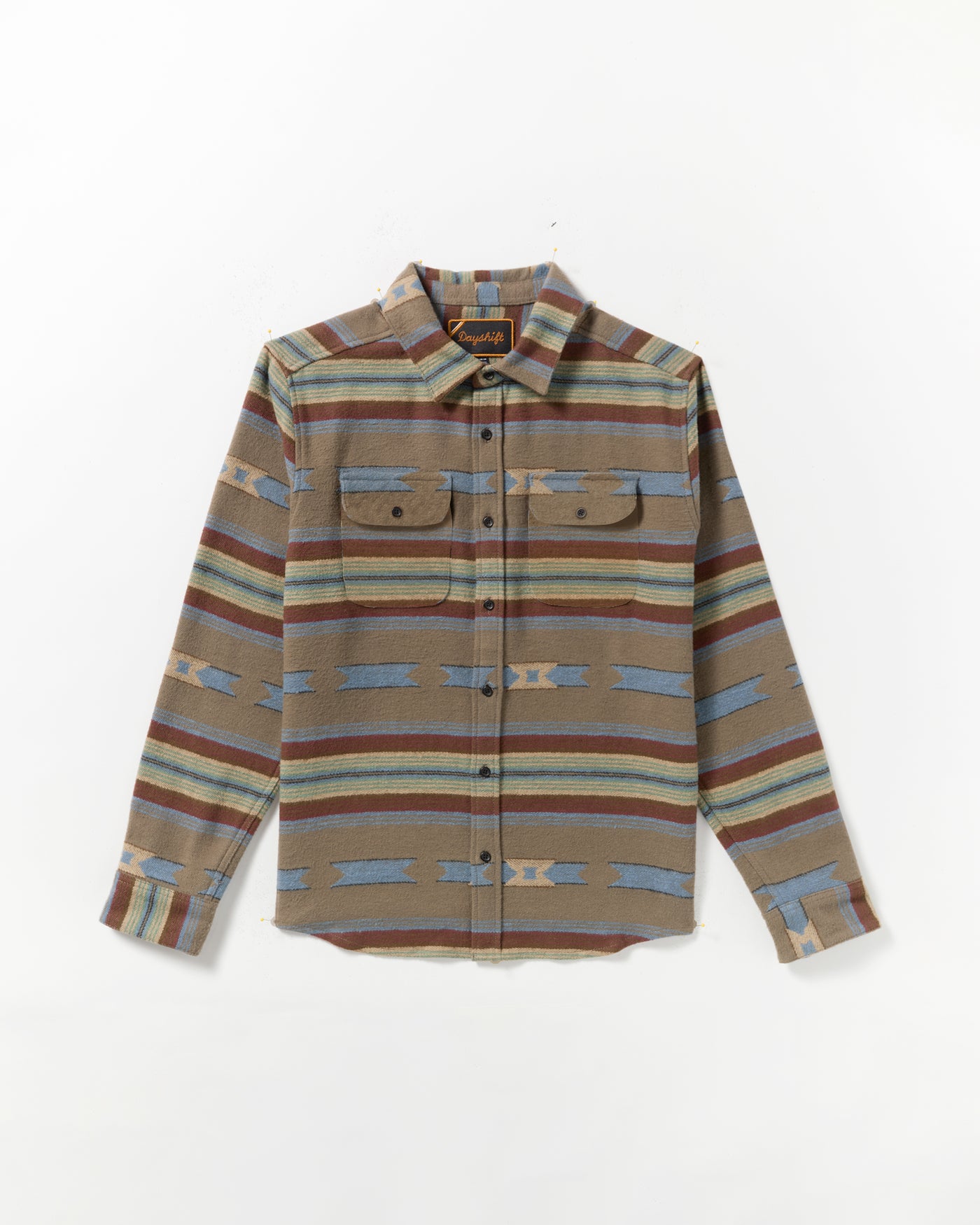 The Dayshift Blanket Flannel Long Sleeve Shirt features a southwestern-inspired pattern in brown, blue, and tan with two chest pockets, button flaps, and a pointed collar. Laid flat on a white background.