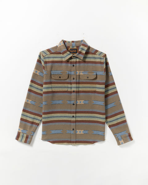 The Dayshift Blanket Flannel Long Sleeve Shirt features a southwestern-inspired pattern in brown, blue, and tan with two chest pockets, button flaps, and a pointed collar. Laid flat on a white background.