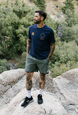 Man standing on a rocky outcrop with trees in the background